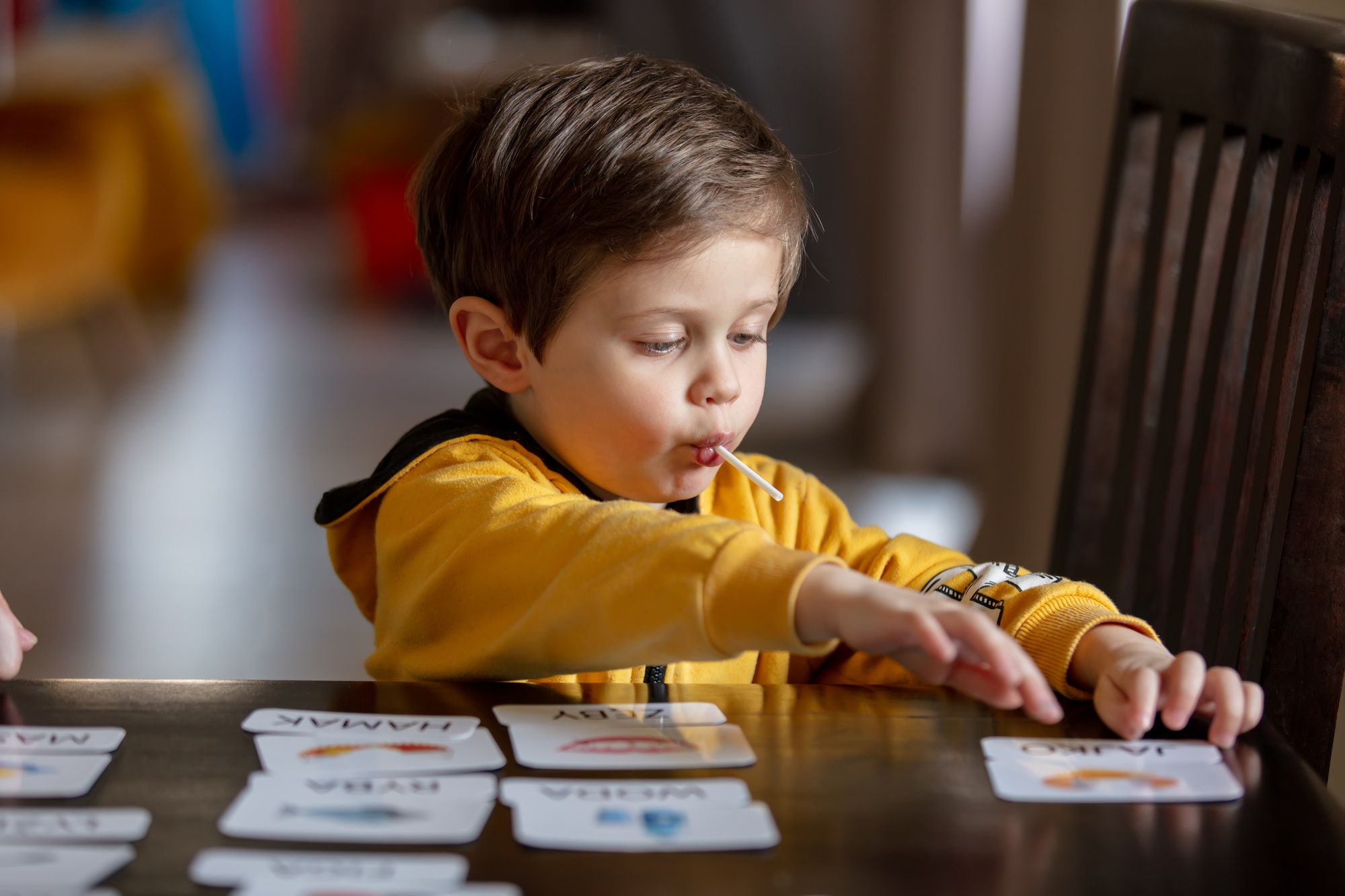 little boy learns words from cards under the ABA therapy program at home at the table