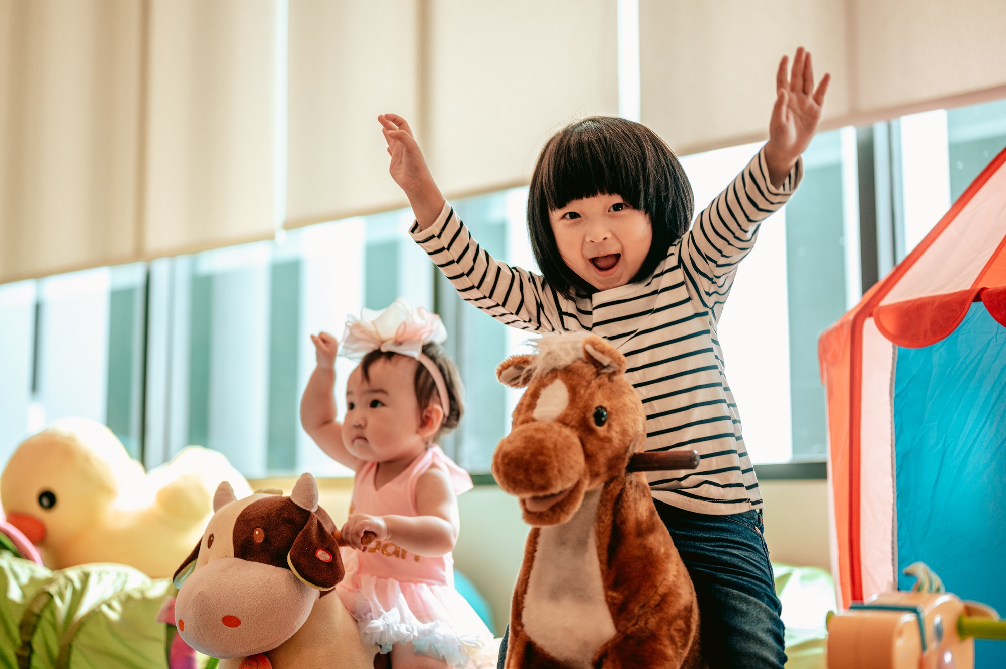 Two children were having fun playing rocking horses together.Family with children at home.