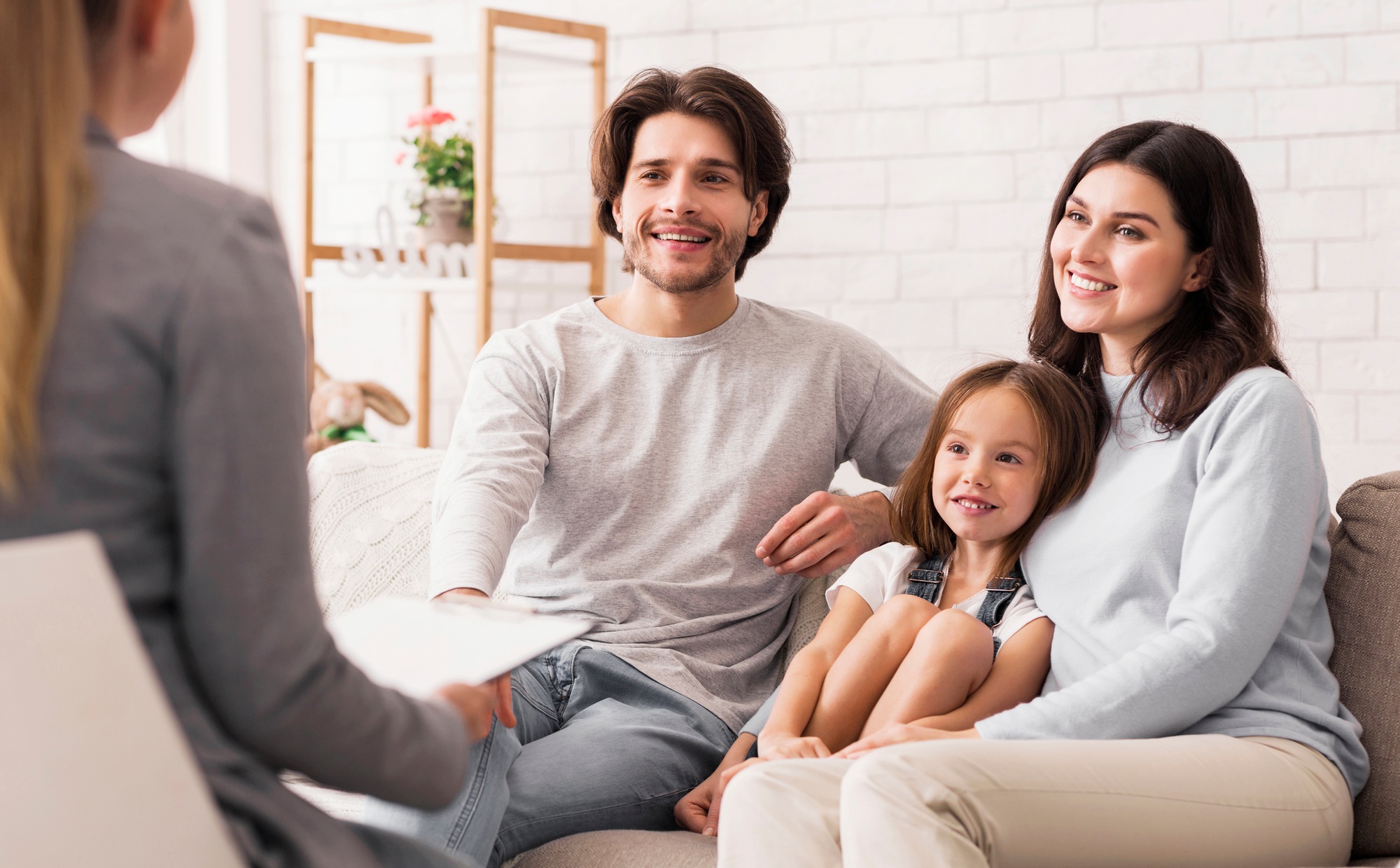 Parents With Little Daughter Sitting At Psycholigist's Office After Successful Therapy