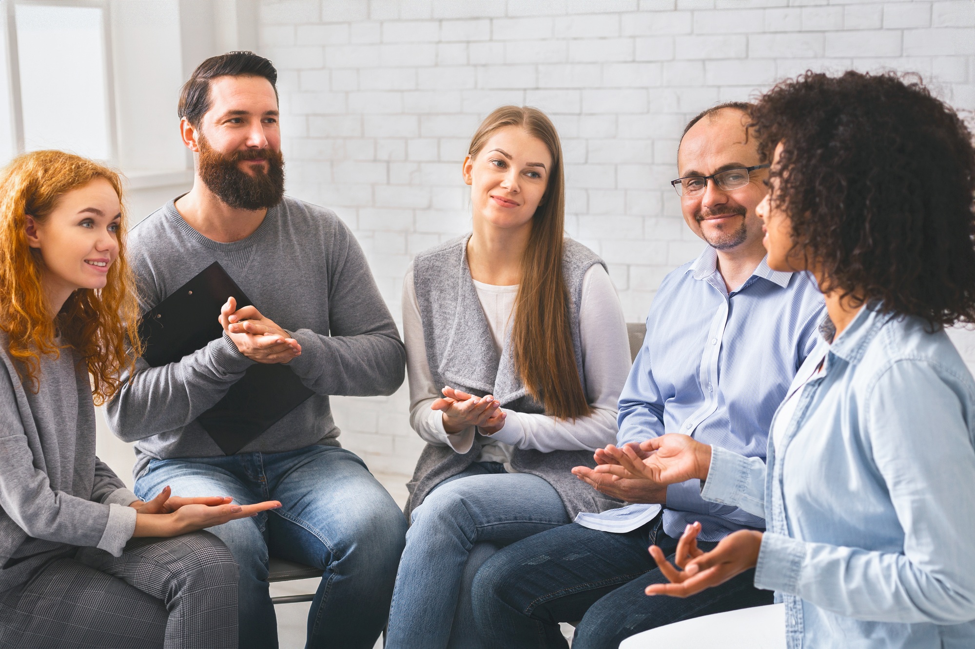 Young woman sharing her story at group therapy session in rehab