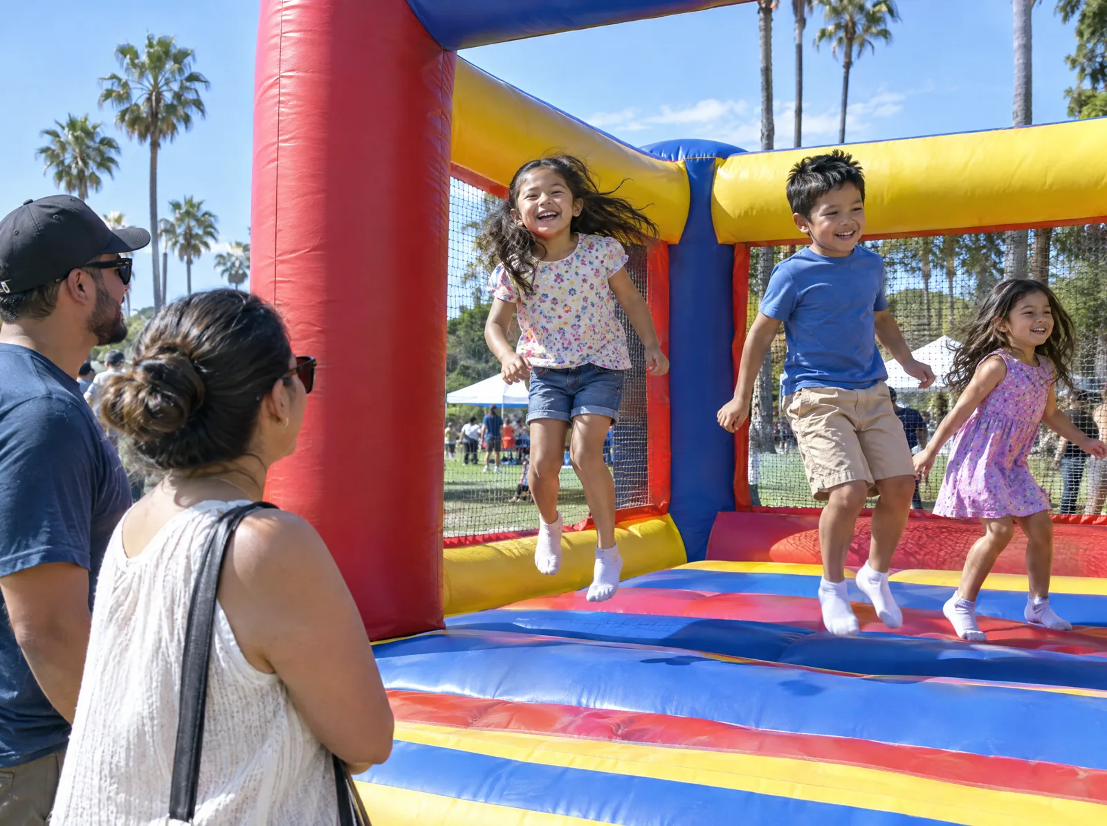 Children jump in a colorful bounce house as parents watch
