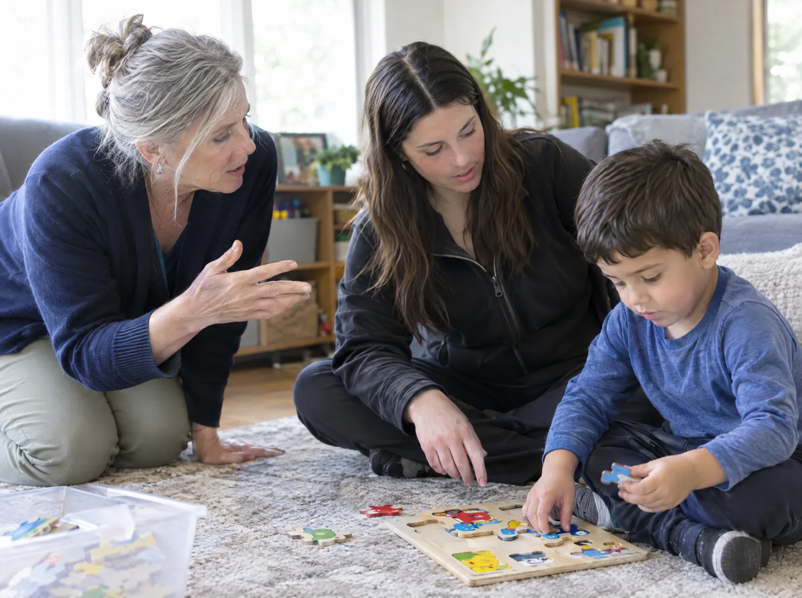 A senior behavior analyst gives quiet feedback to a behavior technician working with a boy on a puzzle