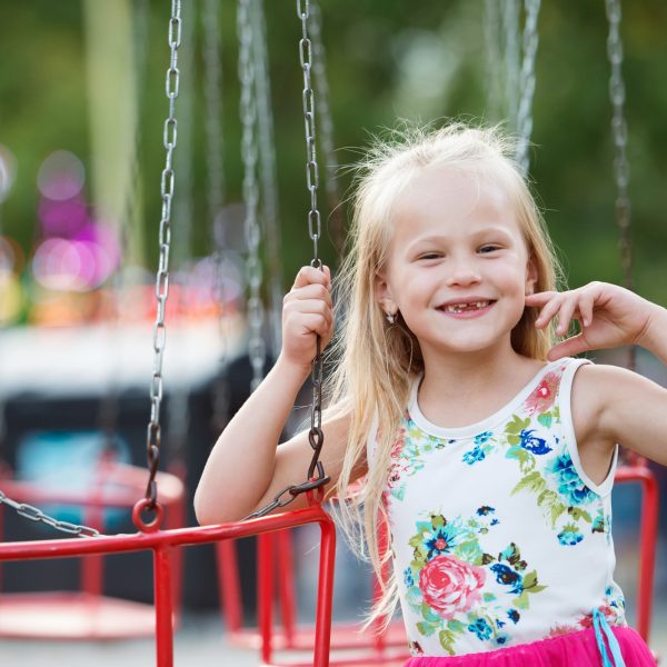 Cute little girl at fun fair, chain swing ride